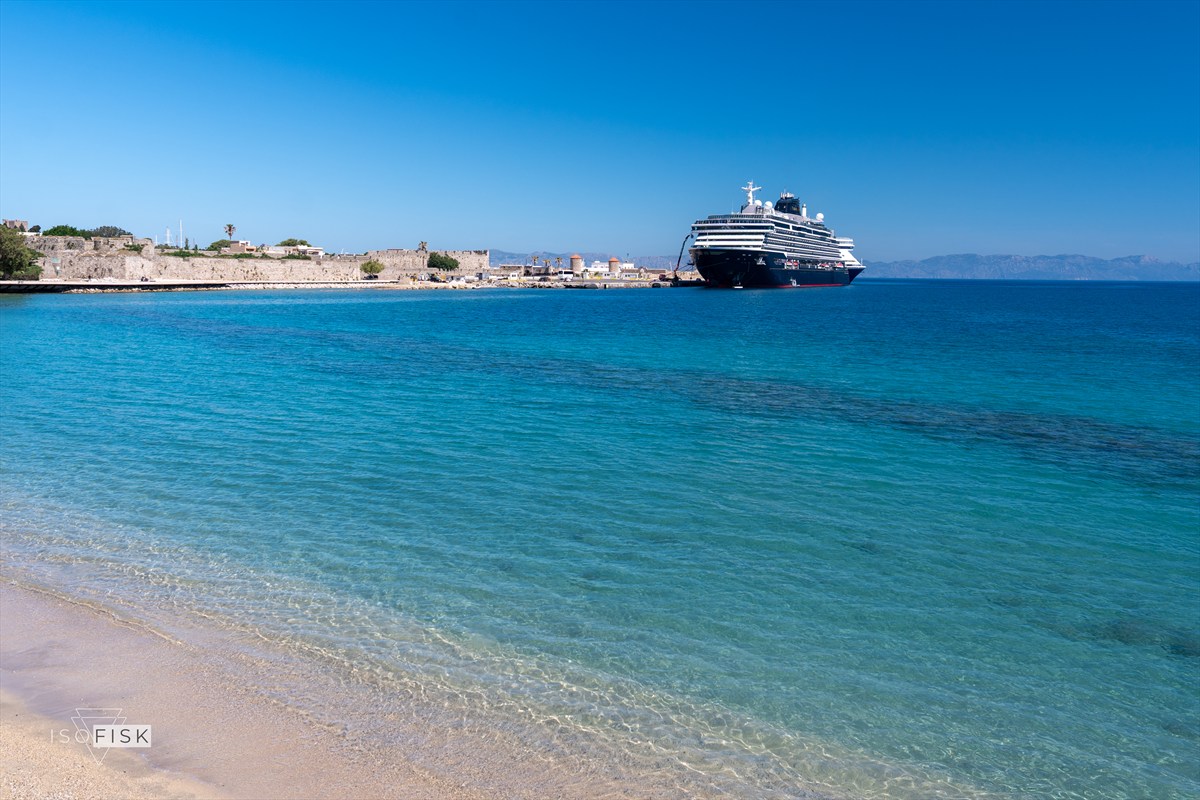Turquoise sea and pale beach with a ship beyond the shoreline
