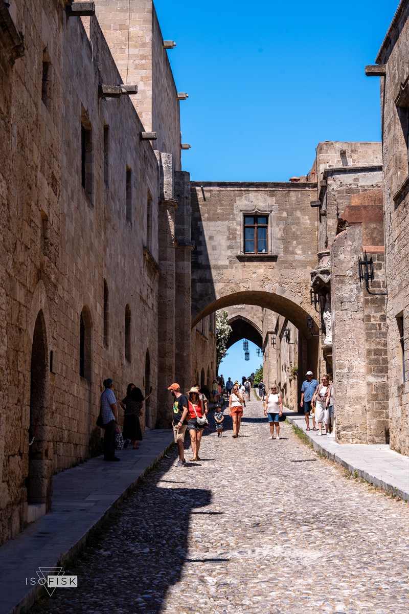 People walking through a stone arch in Rhodes old town