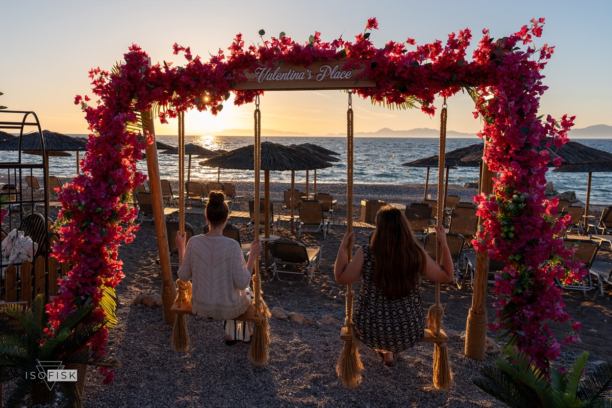Two people sitting together beside the sea at sunset