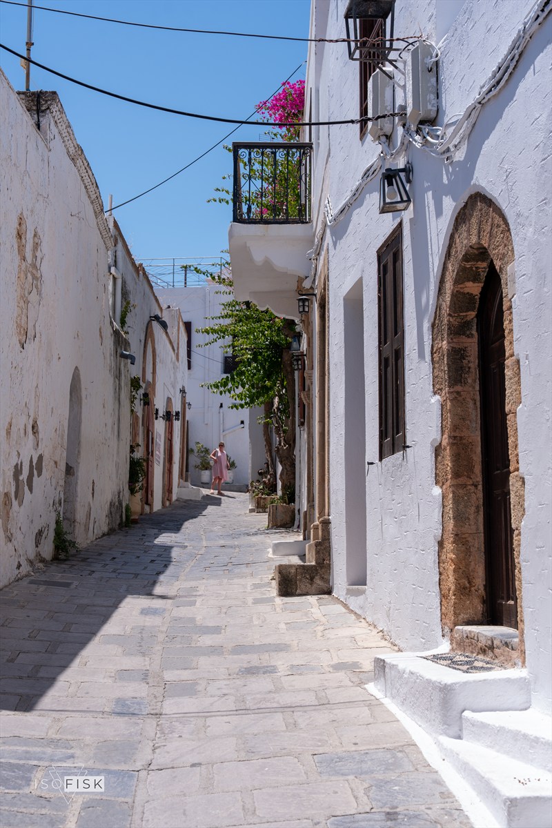 Narrow sunlit lane between whitewashed buildings