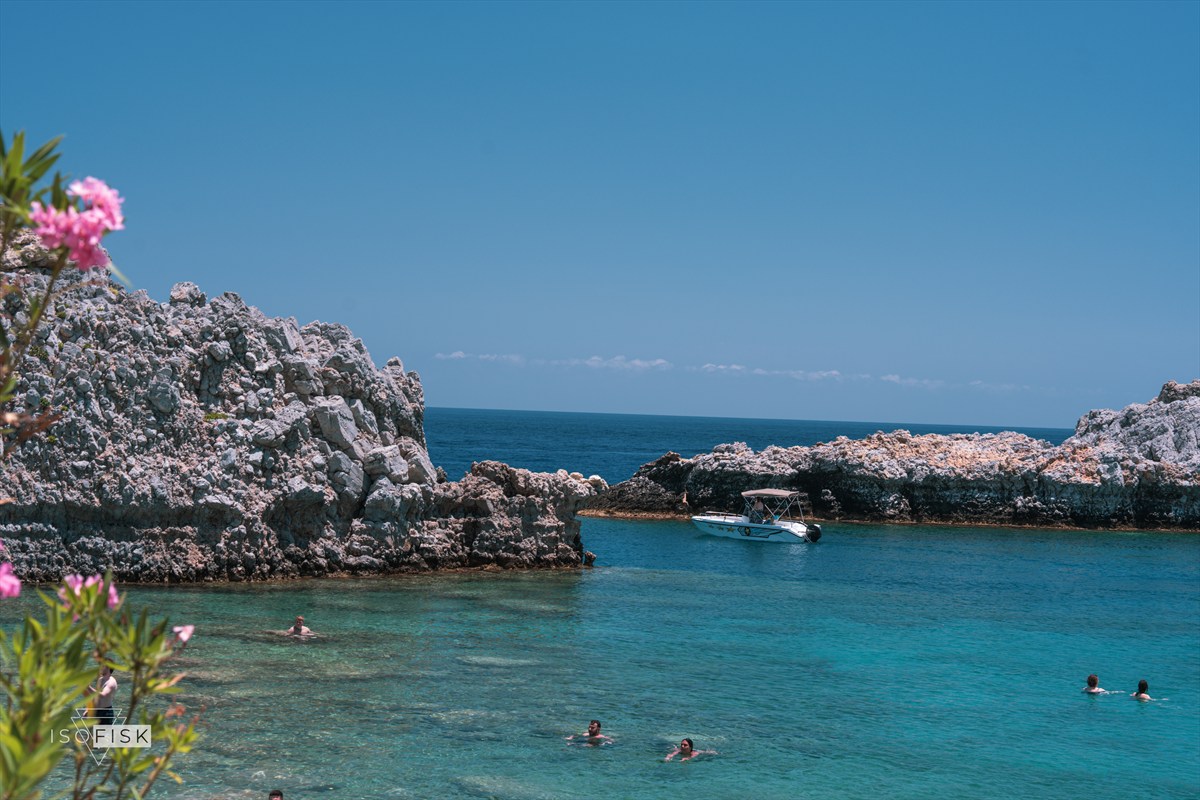 Rocky turquoise inlet with small swimmers