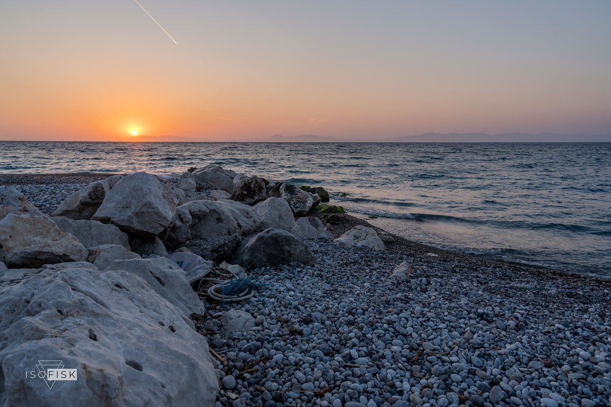Rocky pebble shore beneath a sunset sky