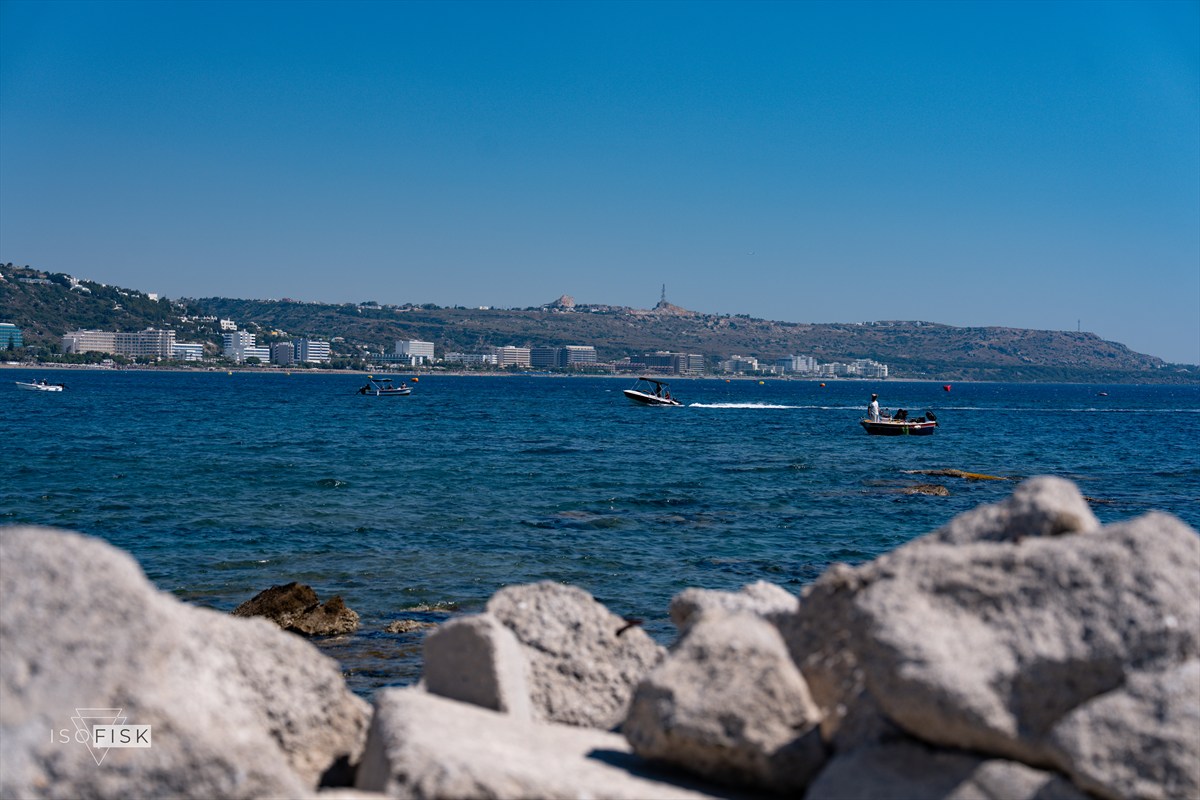 View across blue water towards a distant island and boats