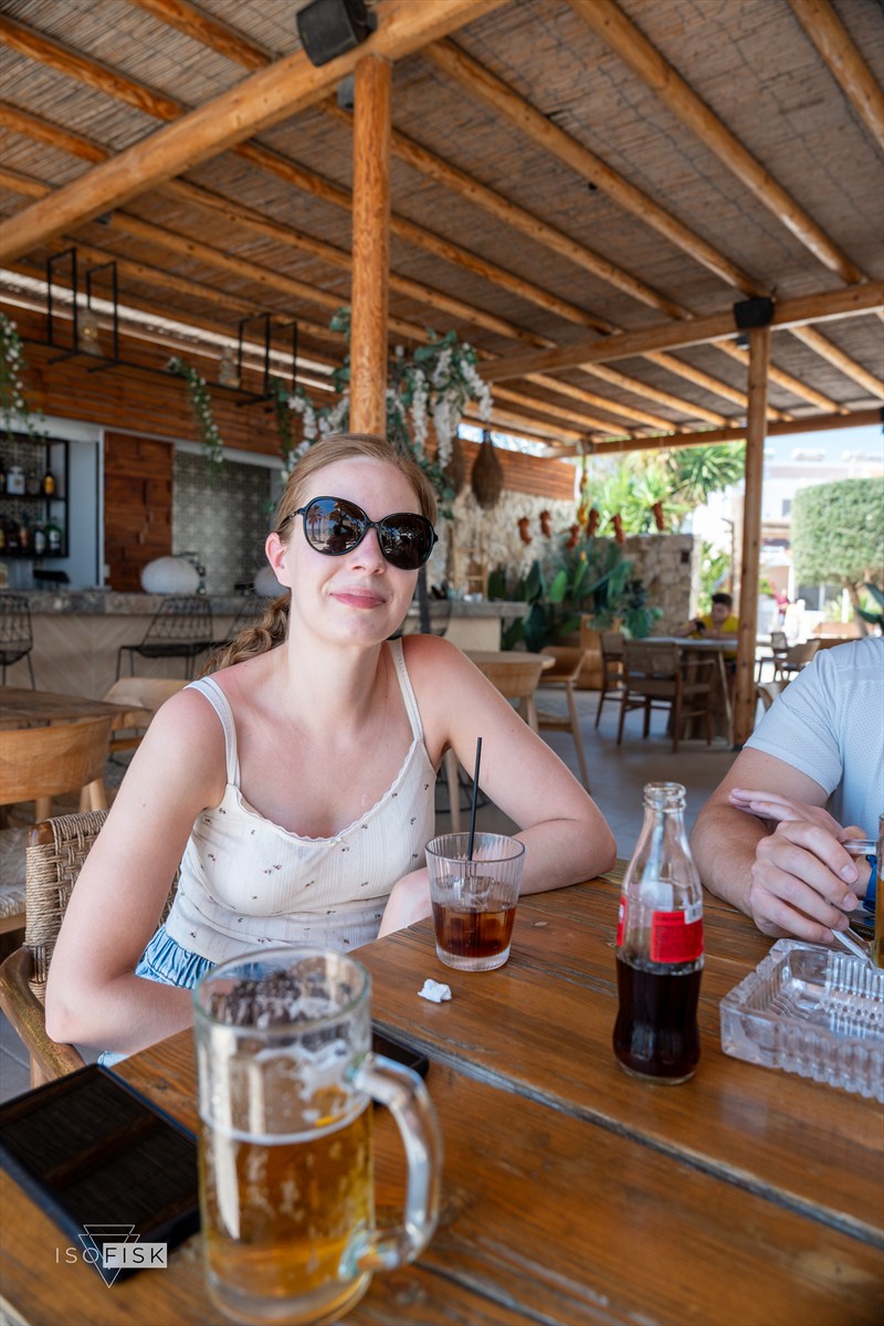 Person enjoying a drink at a shaded beachside table