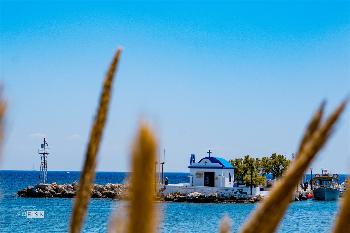 White chapel and lighthouse seen through dry grasses