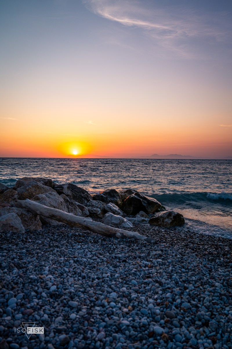 Peach sunset above a rocky shoreline