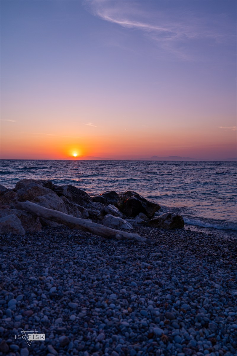 Sunset over rounded rocks and calm water