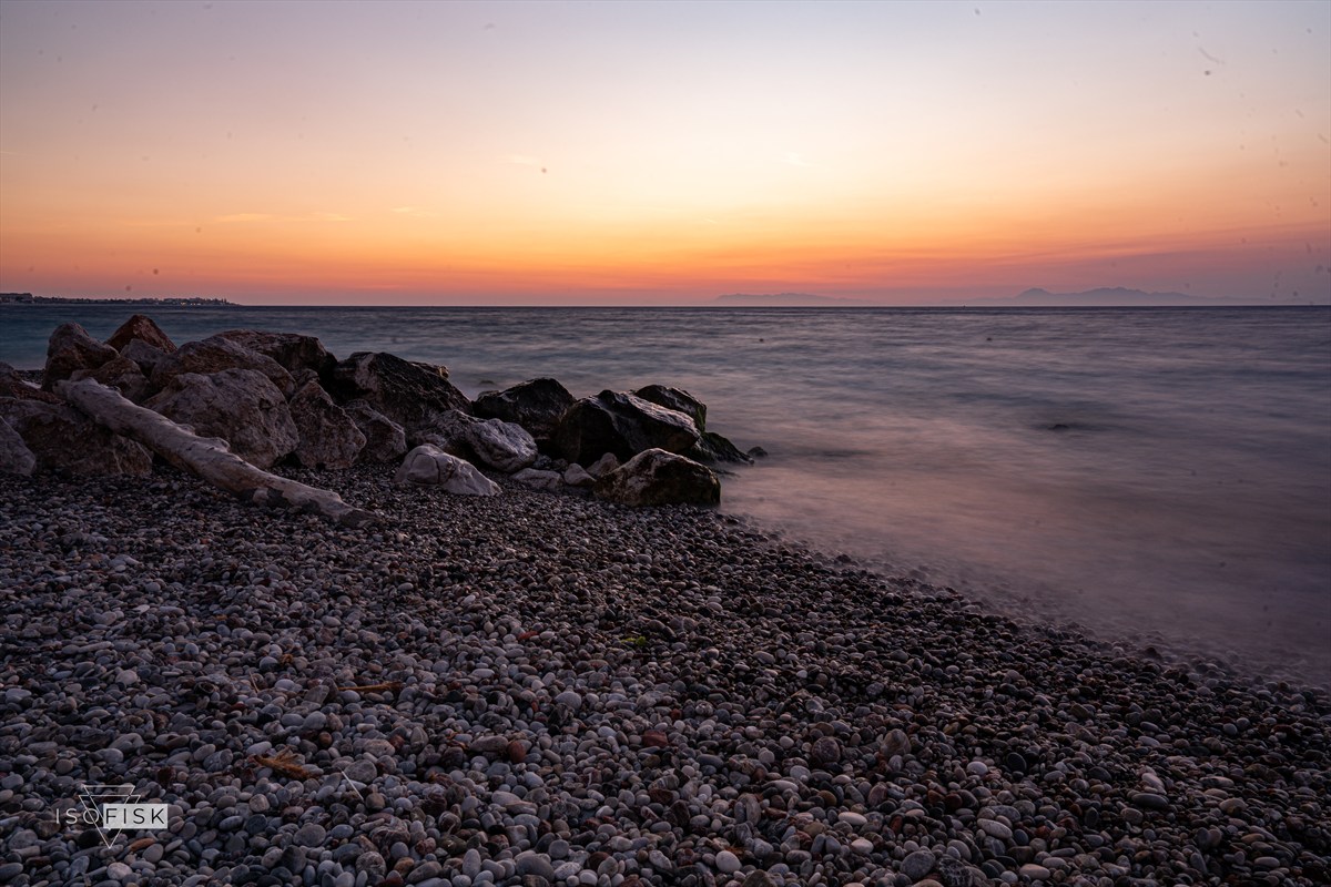 Rocky shore beneath a soft orange dusk sky