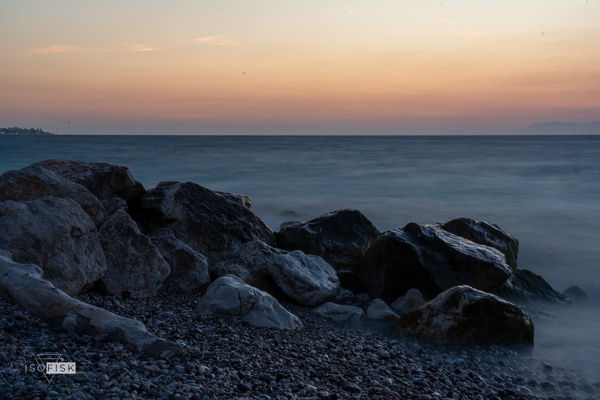 Still soft water around dark rocks at dusk